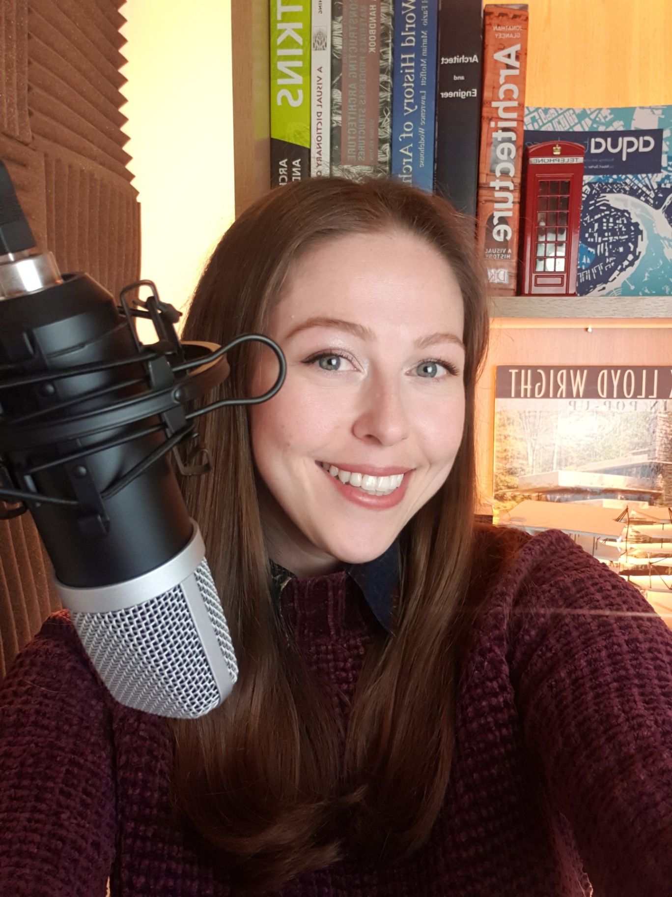 Anna Carina Berkman at the podcast microphone with architecture books